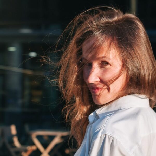 a woman in a white shirt is smiling at the camera