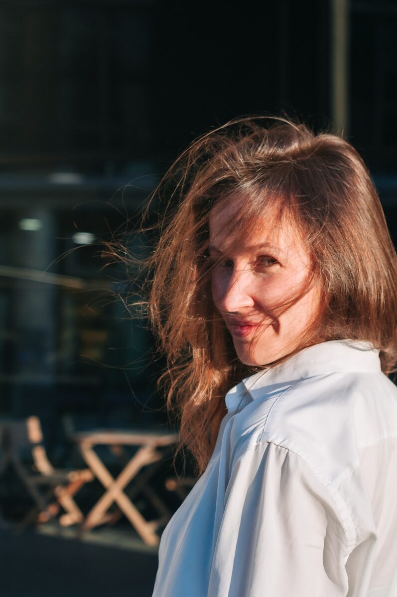 a woman in a white shirt is smiling at the camera