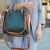 women standing while carrying green and brown leather 2-way shoulder bag