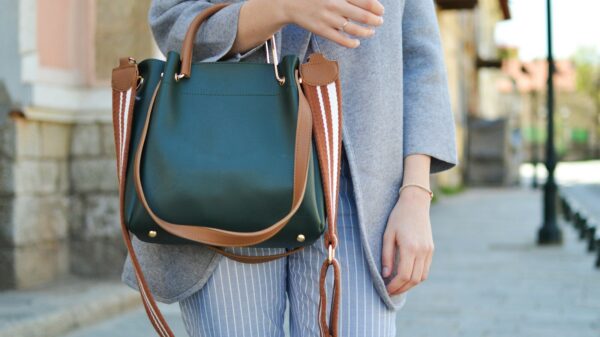 women standing while carrying green and brown leather 2-way shoulder bag