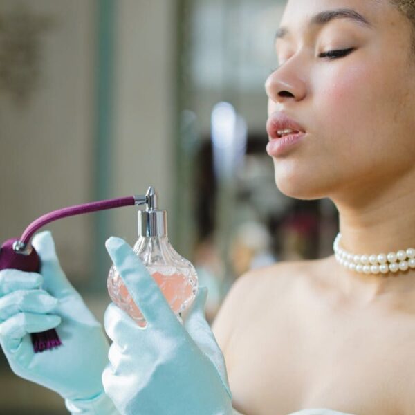 Elegant woman in vintage attire with a classic perfume bottle.
