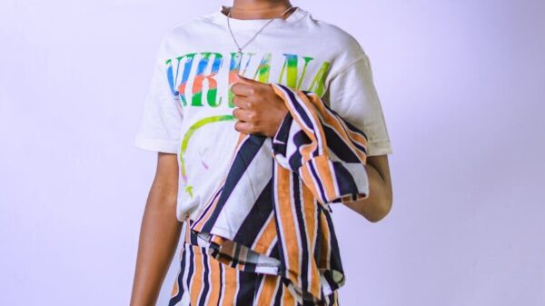 Teenage model poses confidently in a stylish striped ensemble against a white backdrop, exuding modern fashion vibes.