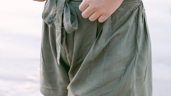 Close view of green tie-front shorts on sandy beach, exuding a relaxed summer vibe.