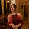 Portrait of an elegant woman in a luxurious and ornately decorated interior with warm lighting.