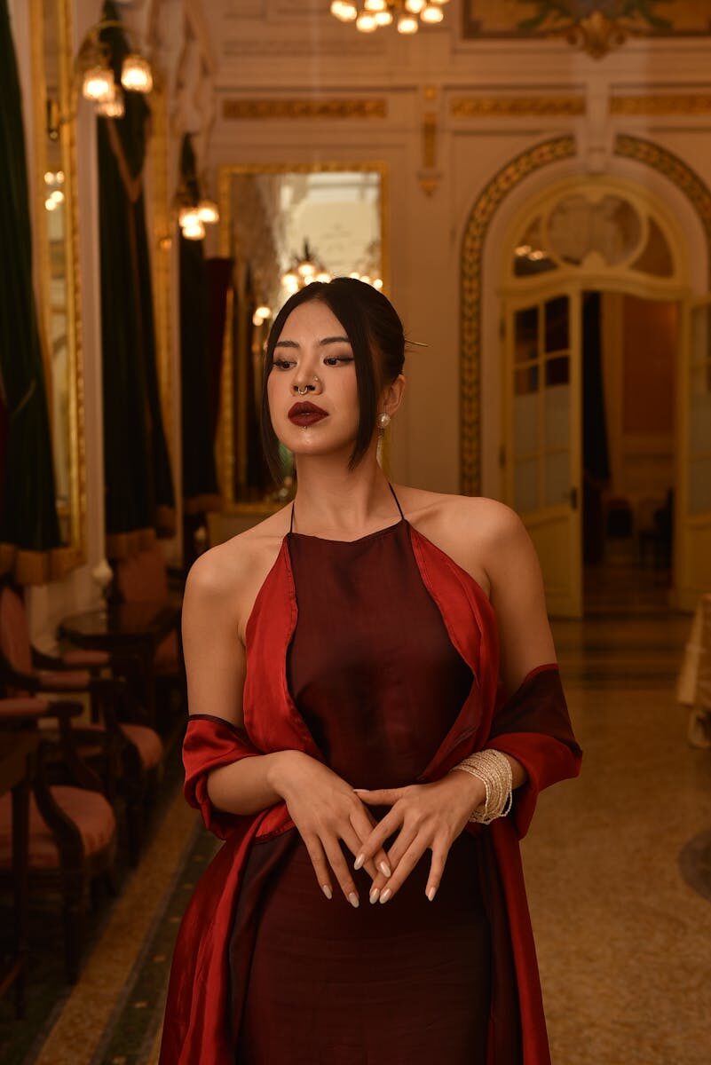 Portrait of an elegant woman in a luxurious and ornately decorated interior with warm lighting.