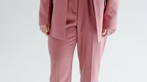 Confident woman in a stylish pink blazer and pants with white sneakers.