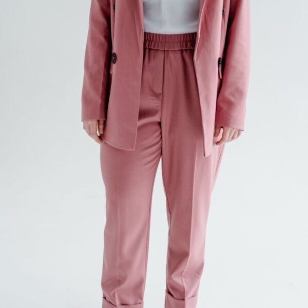 Confident woman in a stylish pink blazer and pants with white sneakers.
