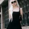 Fashionable woman in a black dress and sunglasses posing on an urban street. Elegant and chic look.