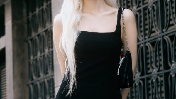 Fashionable woman in a black dress and sunglasses posing on an urban street. Elegant and chic look.