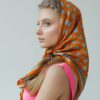 Young woman with orange patterned headscarf and pink dress.