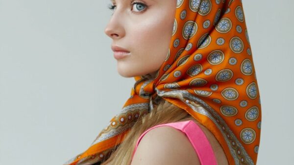 Young woman with orange patterned headscarf and pink dress.
