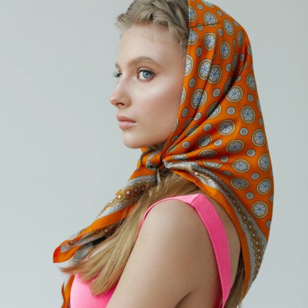 Young woman with orange patterned headscarf and pink dress.