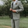 standing man holding his notched lapel suit jacket's button