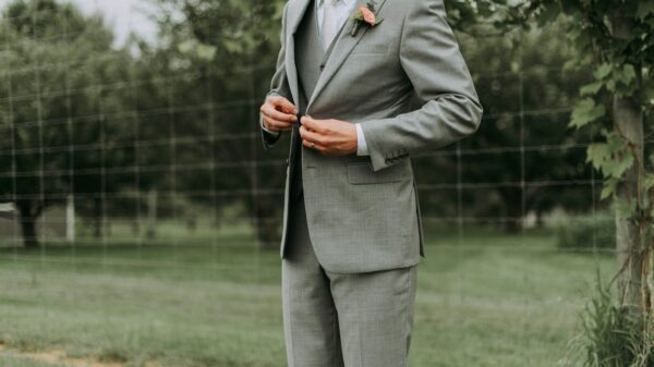 standing man holding his notched lapel suit jacket's button