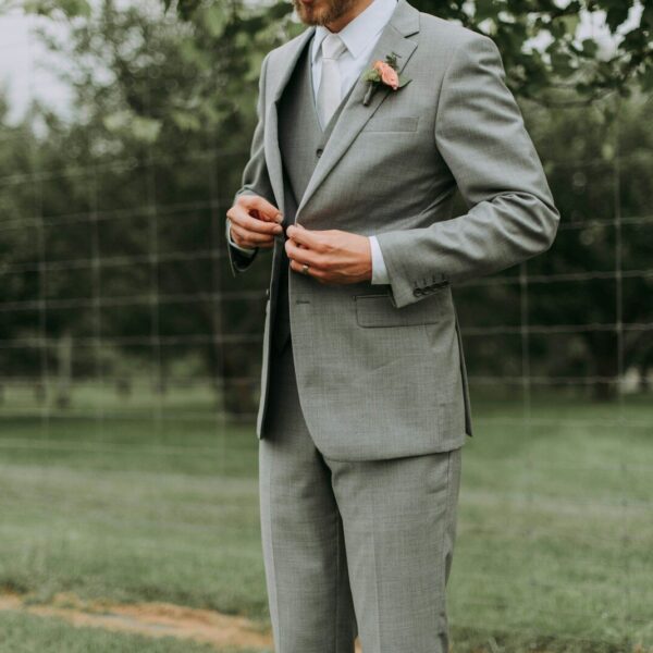 standing man holding his notched lapel suit jacket's button