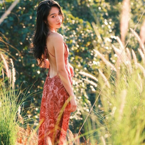Young woman in a dress stands in tall grass
