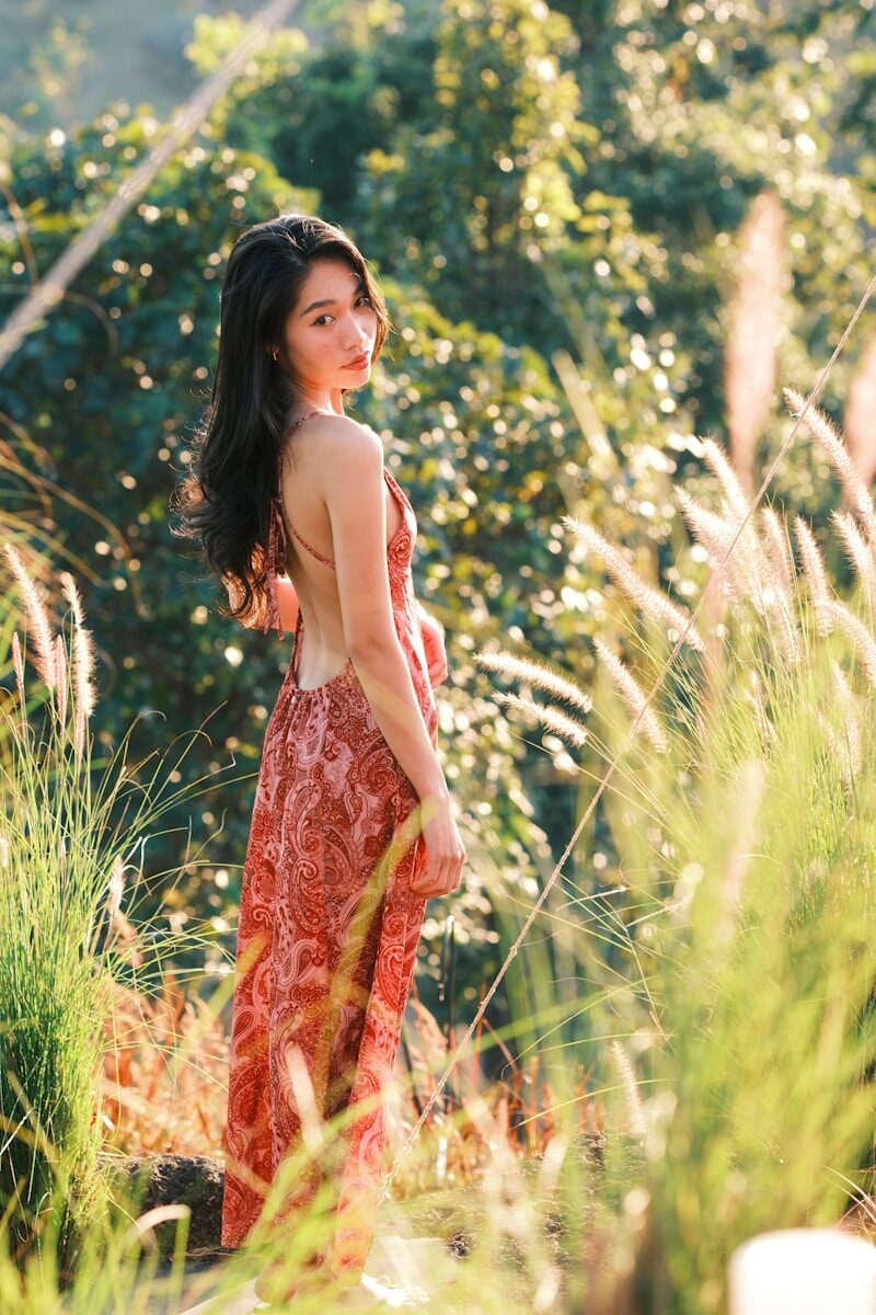 Young woman in a dress stands in tall grass