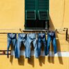 five blue denim jeans hanged on grey cable near window