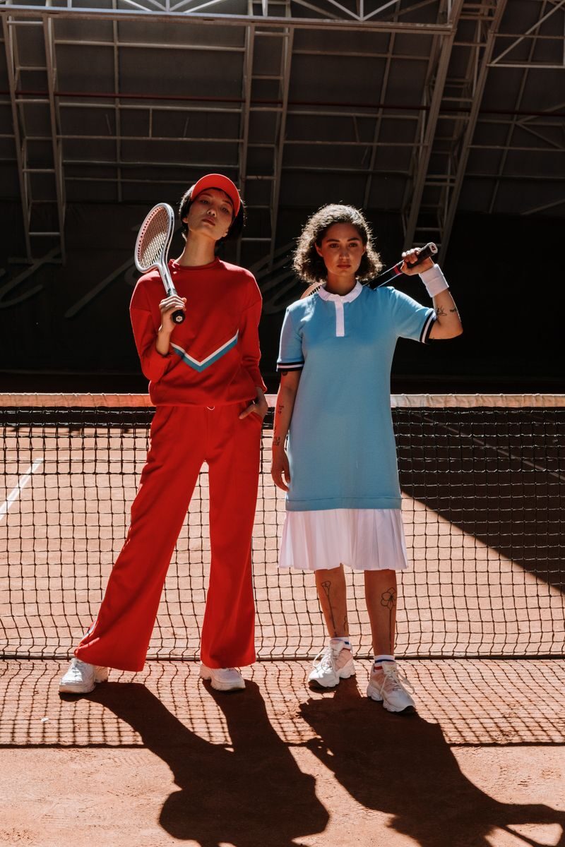 Two athletes in vibrant sport wear posing confidently on a tennis court.