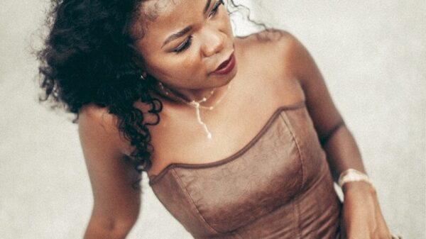 A woman poses in brown corset and pants.