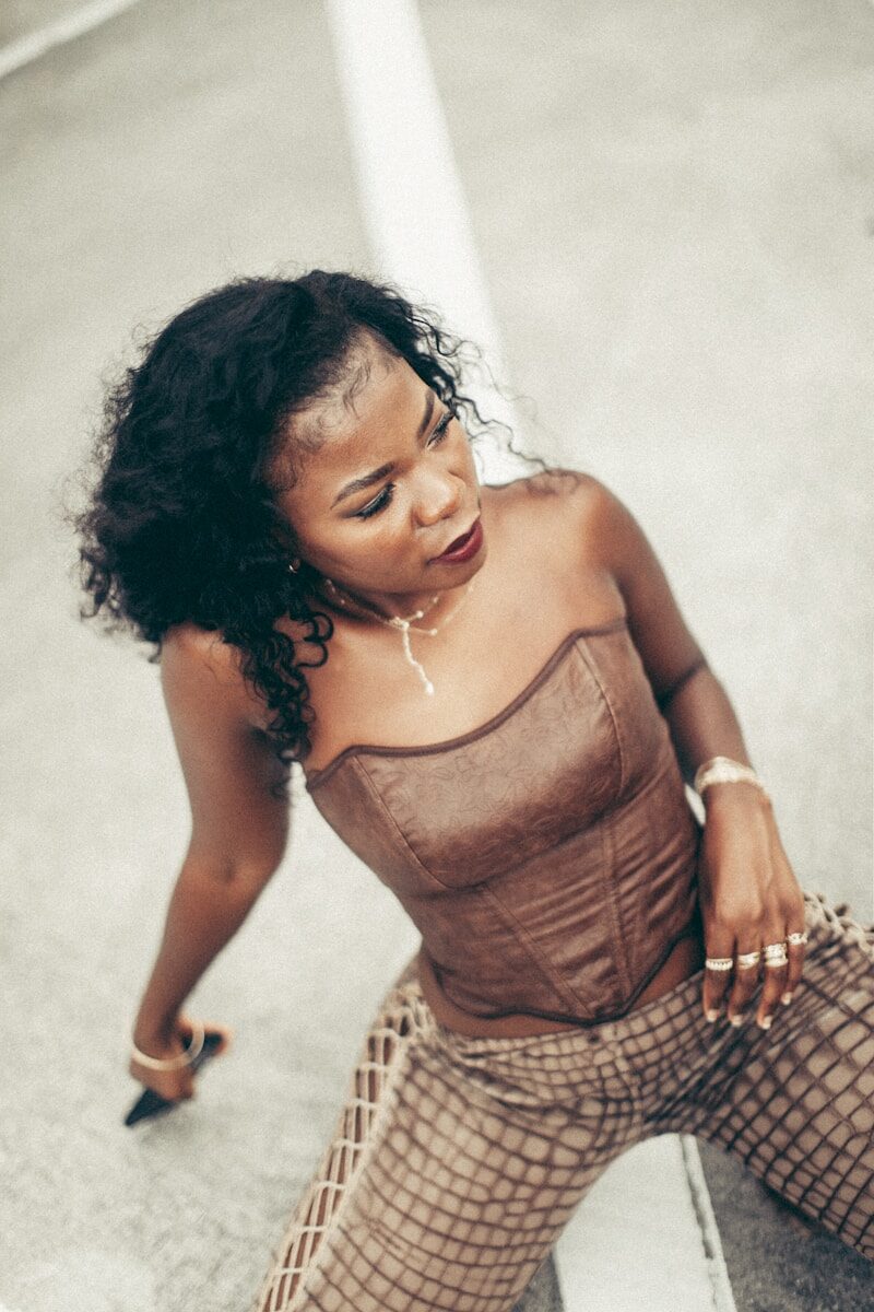 A woman poses in brown corset and pants.