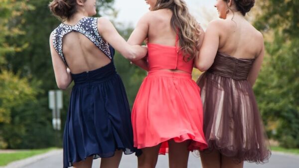 three women wearing red, brown, and blue dresses walking on concrete road during daytime