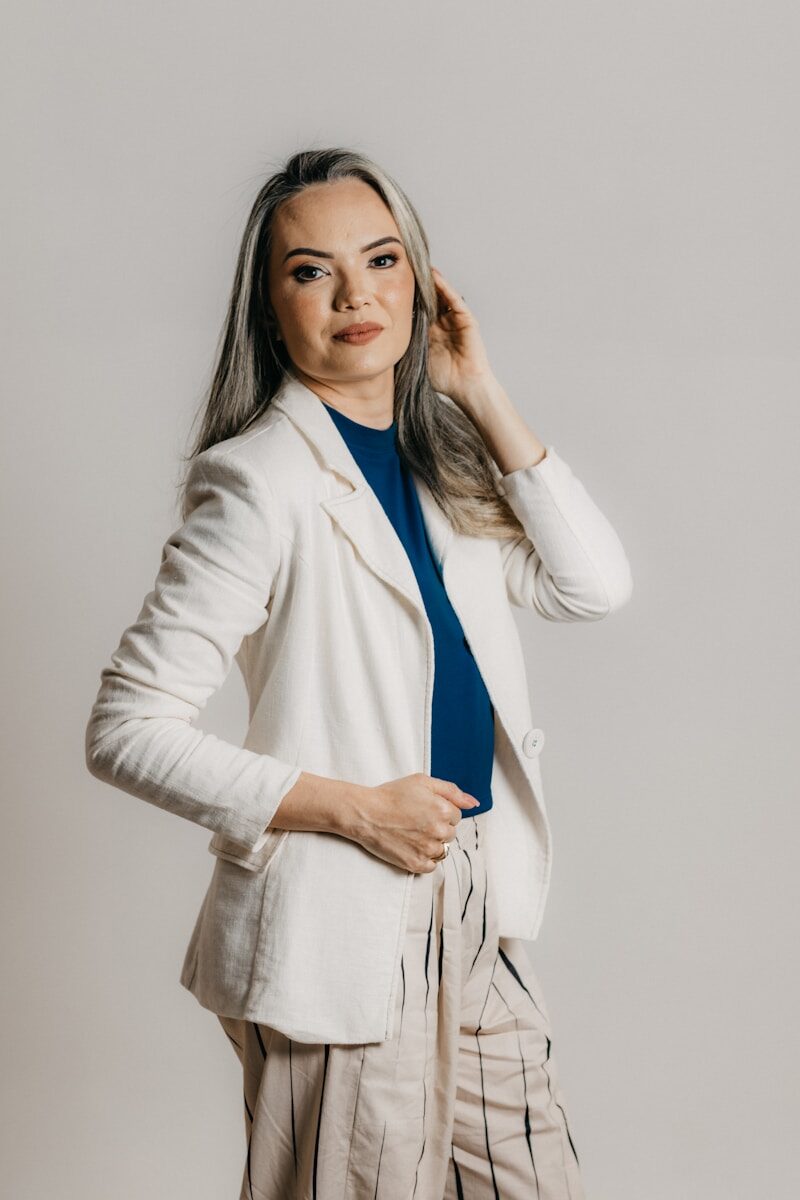 a woman in a white blazer is posing for a picture