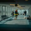 a man walking down a long hallway with lots of windows