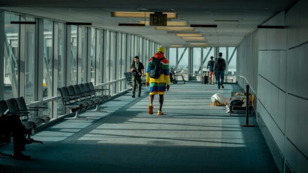 a man walking down a long hallway with lots of windows