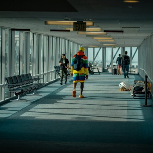 a man walking down a long hallway with lots of windows