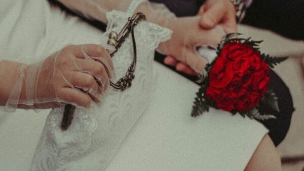 Elegant couple holding hands, one with a red flower wristlet.