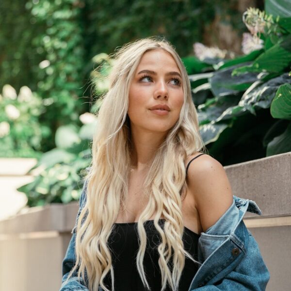 woman in blue denim jacket sitting on brown wooden bench