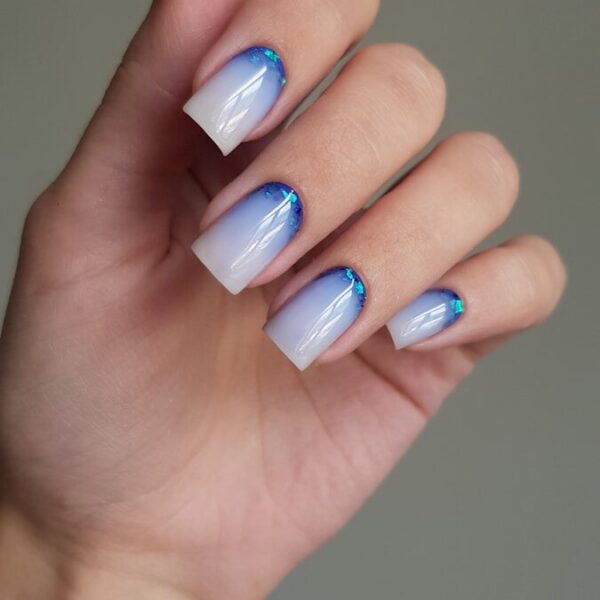 Woman's hand with blue and white ombre nails