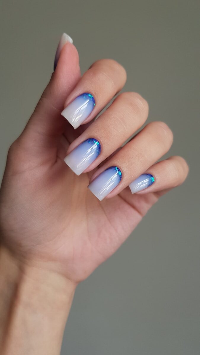 Woman's hand with blue and white ombre nails