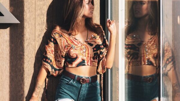 woman in brown and black leopard long sleeve shirt and blue denim shorts standing beside glass