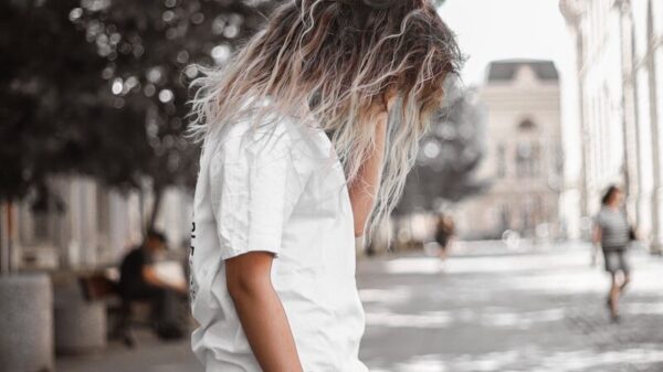 woman in white t-shirt and brown shorts standing on street during daytime