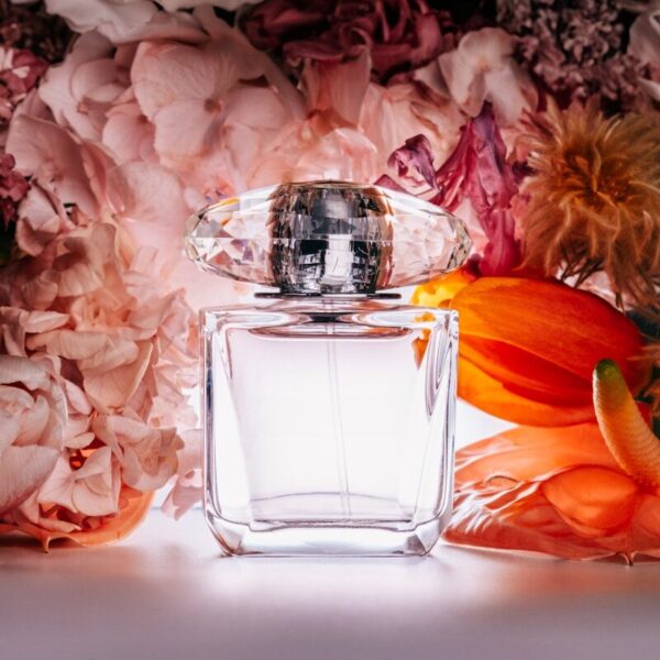a bottle of perfume sitting next to a bunch of flowers
