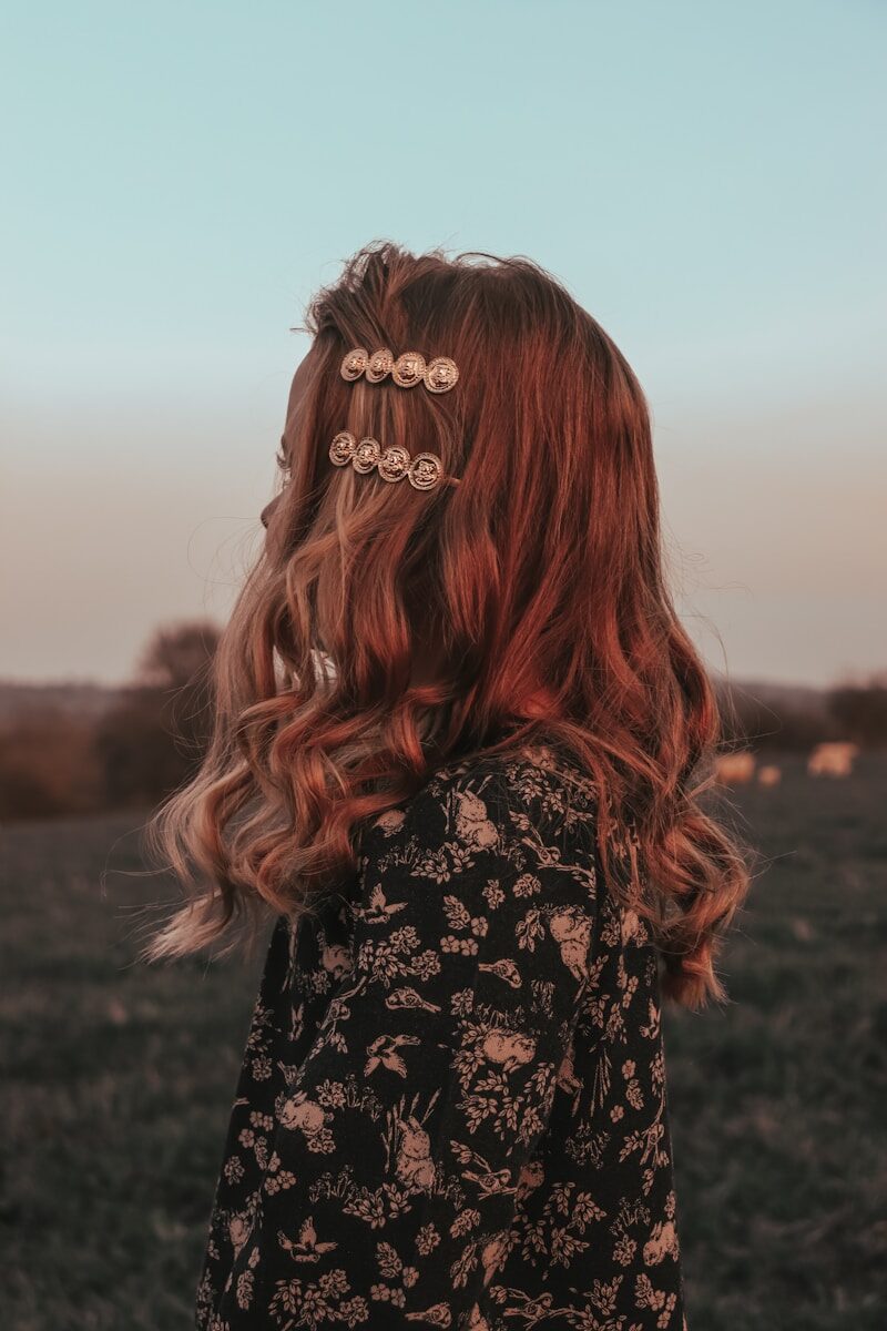 a woman with red hair standing in a field