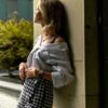 a woman leaning against a wall with her hand on her hip