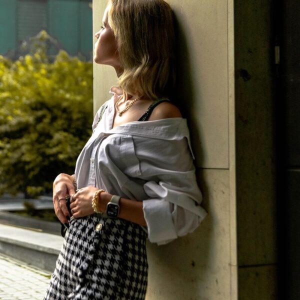 a woman leaning against a wall with her hand on her hip