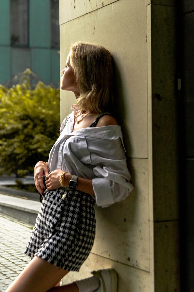 a woman leaning against a wall with her hand on her hip