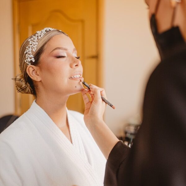 Makeup artist applying lipstick to a woman's lips.