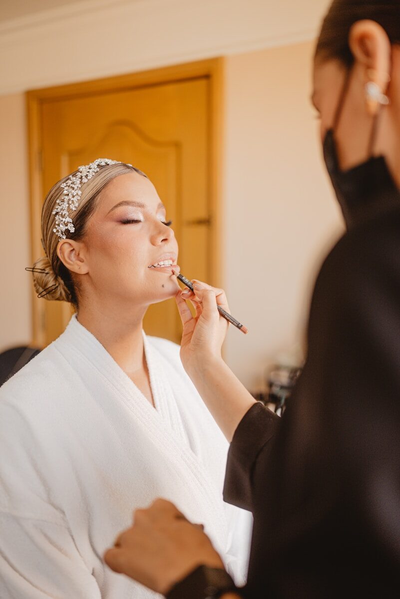 Makeup artist applying lipstick to a woman's lips.