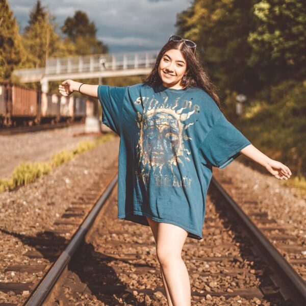 woman in blue long sleeve dress standing on train rail during daytime