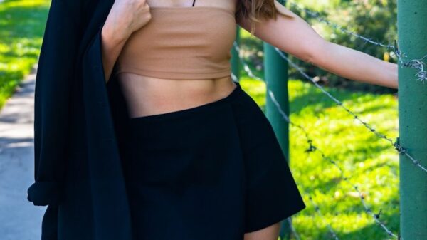 A woman leaning against a fence posing for a picture