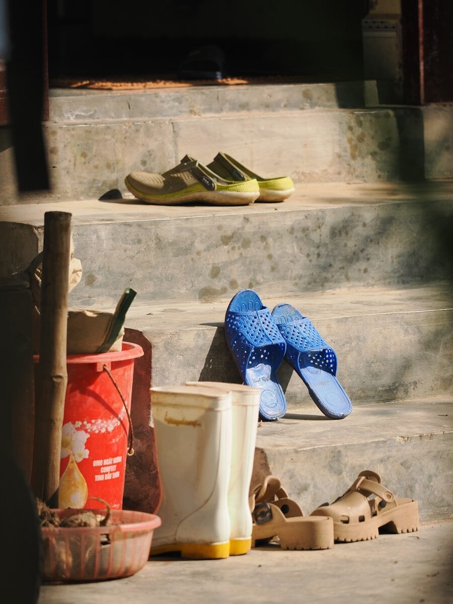 Various shoes and boots on outdoor steps.