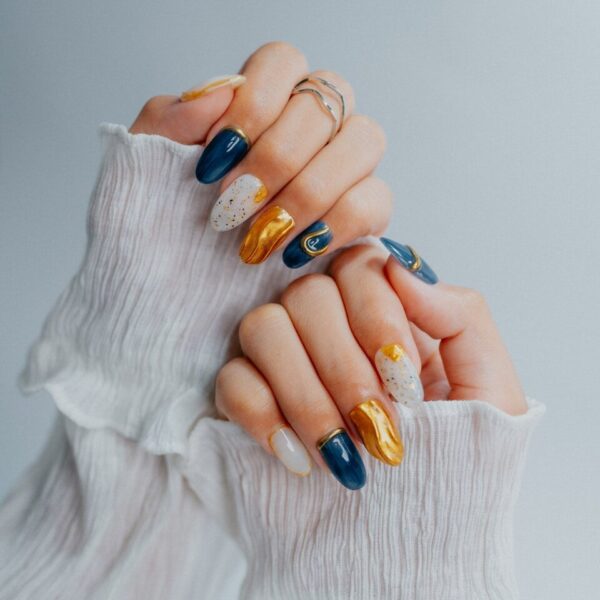 Woman's hands with ornate navy, gold, and white nails