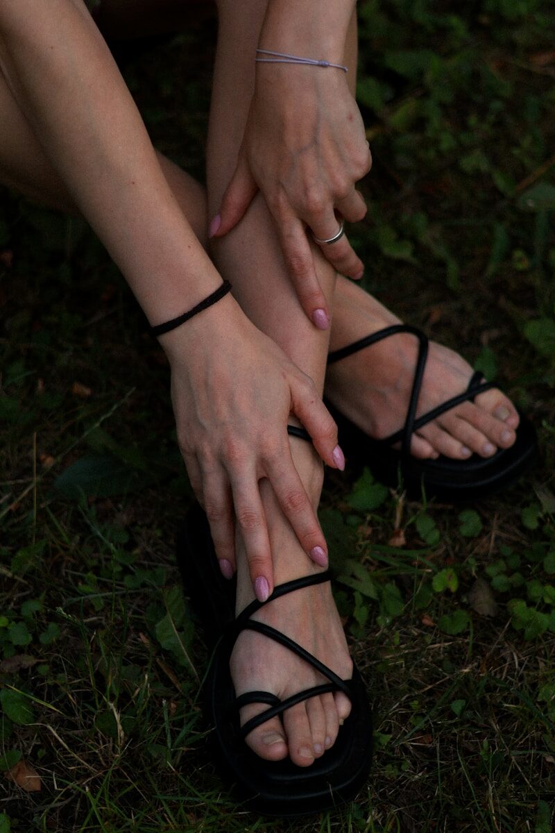 a woman sitting on the ground with her hands on her feet