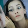 a woman is putting mascara on her face