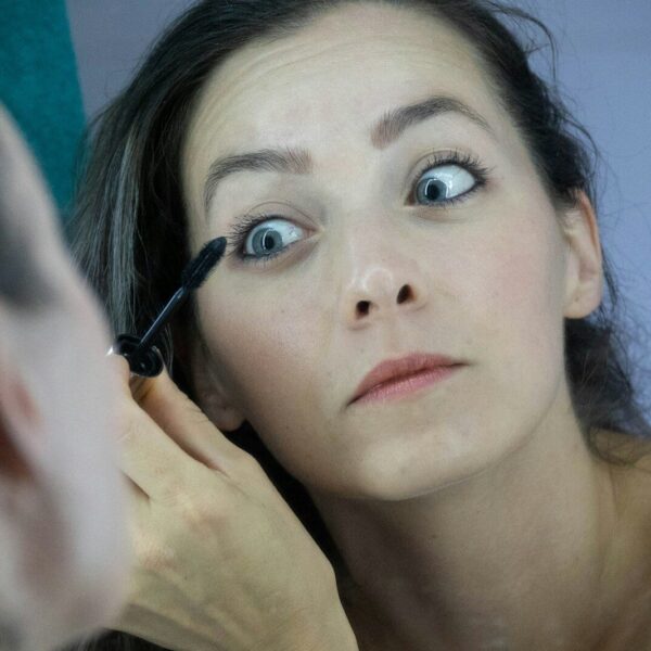 a woman is putting mascara on her face